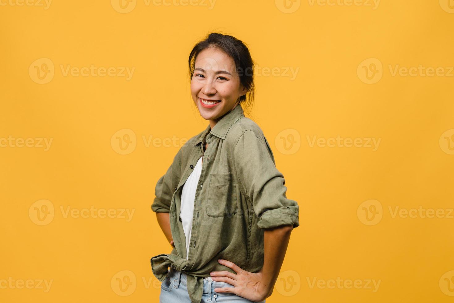 giovane donna asiatica con espressione positiva, sorriso ampiamente, vestita con abiti casual e guardando la telecamera su sfondo giallo. felice adorabile donna felice esulta successo. concetto di espressione facciale. foto