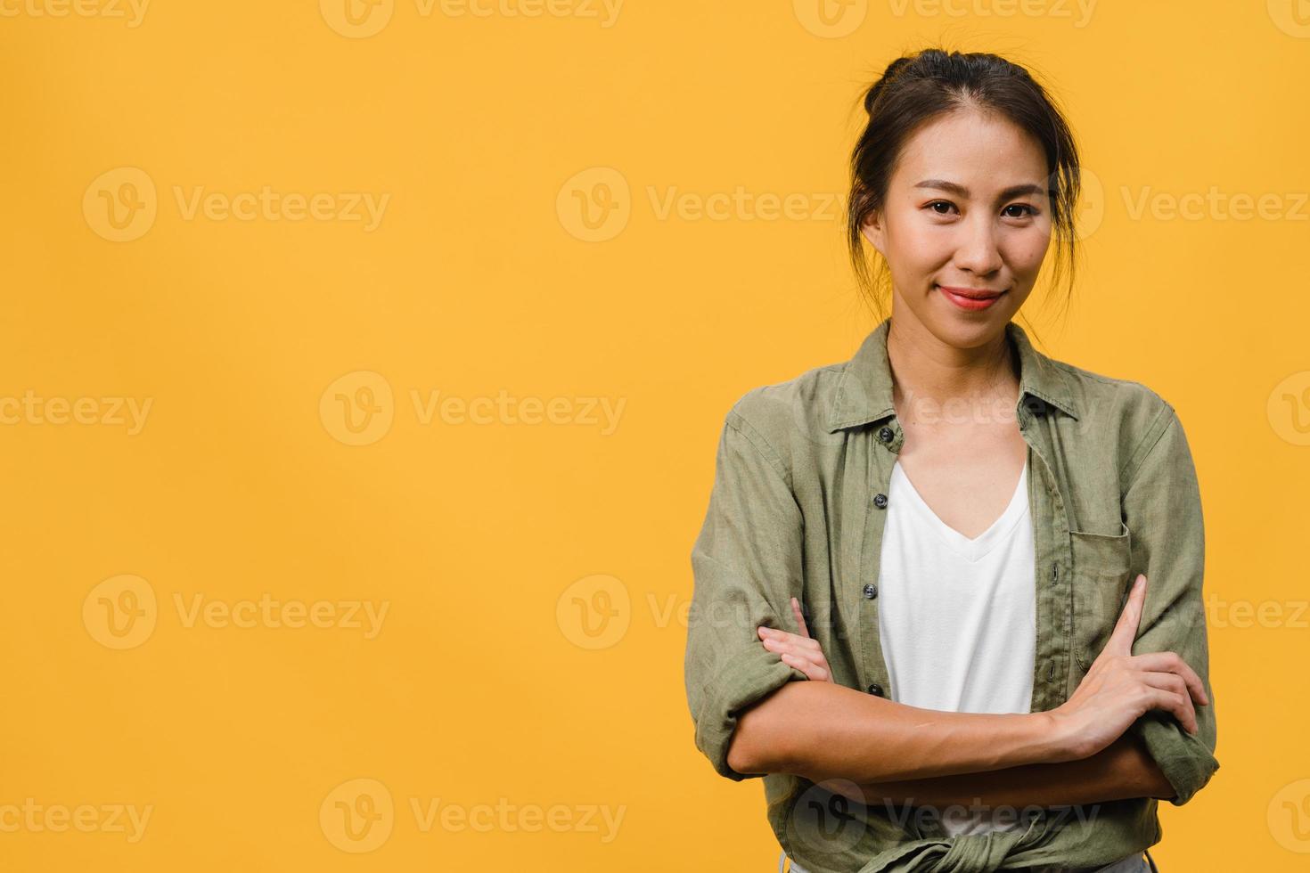 ritratto di giovane donna asiatica con espressione positiva, braccia incrociate, sorriso ampiamente, vestita con abiti casual e guardando la telecamera su sfondo giallo. felice adorabile donna felice esulta successo. foto