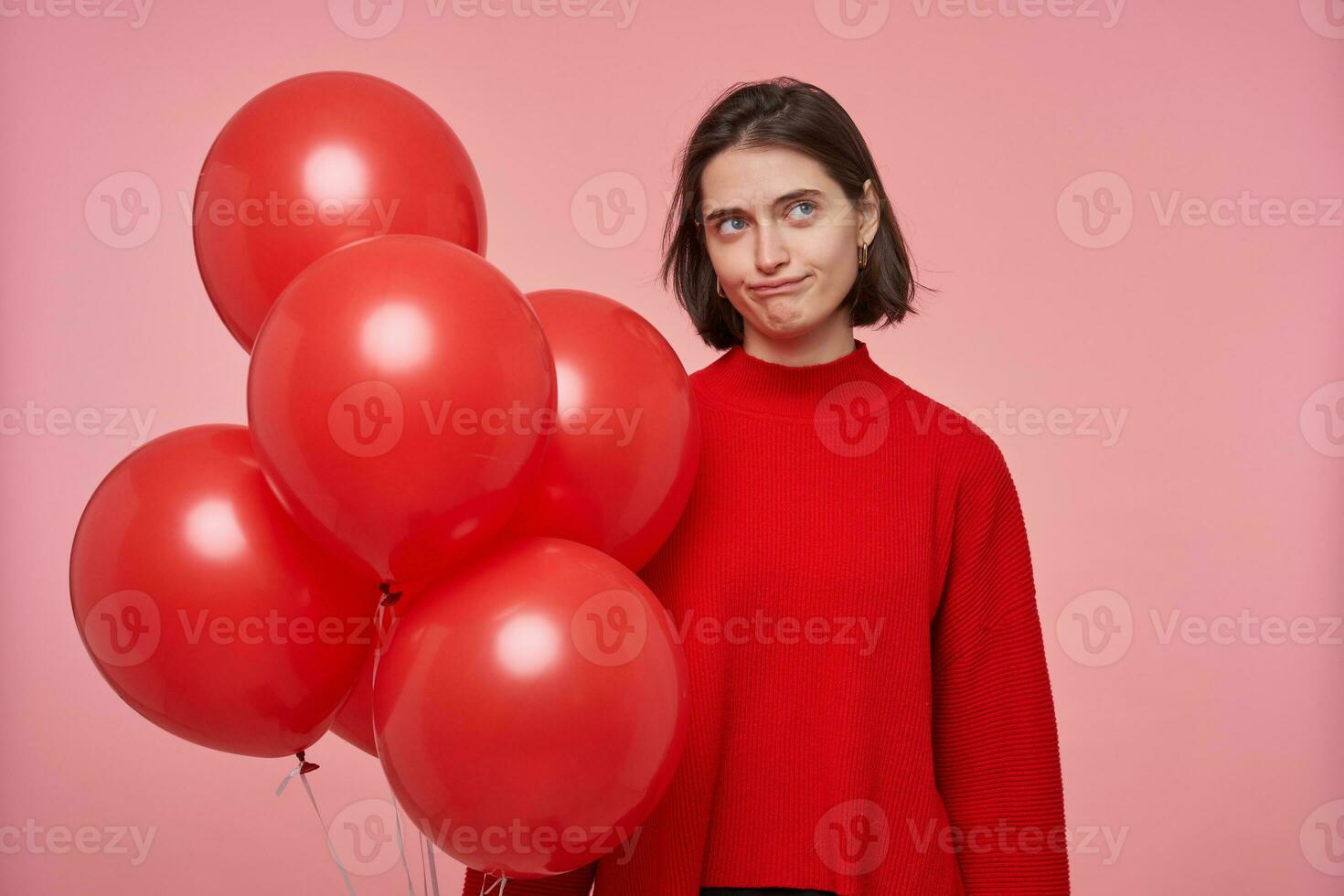 studio ritratto di giovane femmina Tenere rosso palloncini fells confuso e infelice. isolato al di sopra di rosa sfondo foto