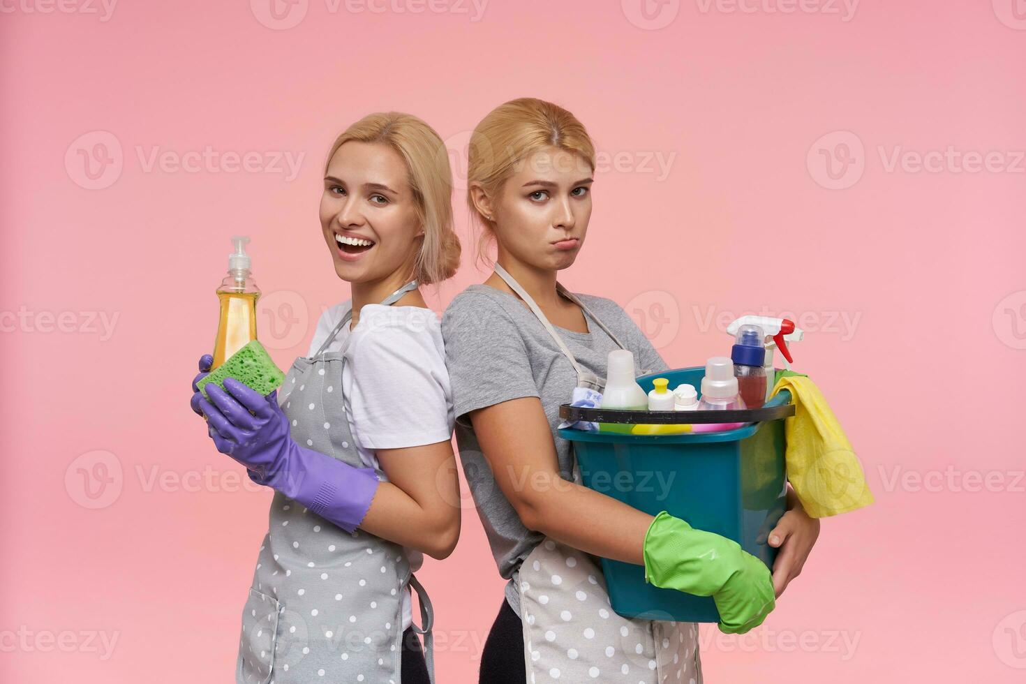 studio foto di bella giovane bionda pulizia le signore pendente indietro per indietro e esprimendo diverso emozioni, conservazione domestico sostanze chimiche nel loro mani mentre in posa al di sopra di rosa sfondo