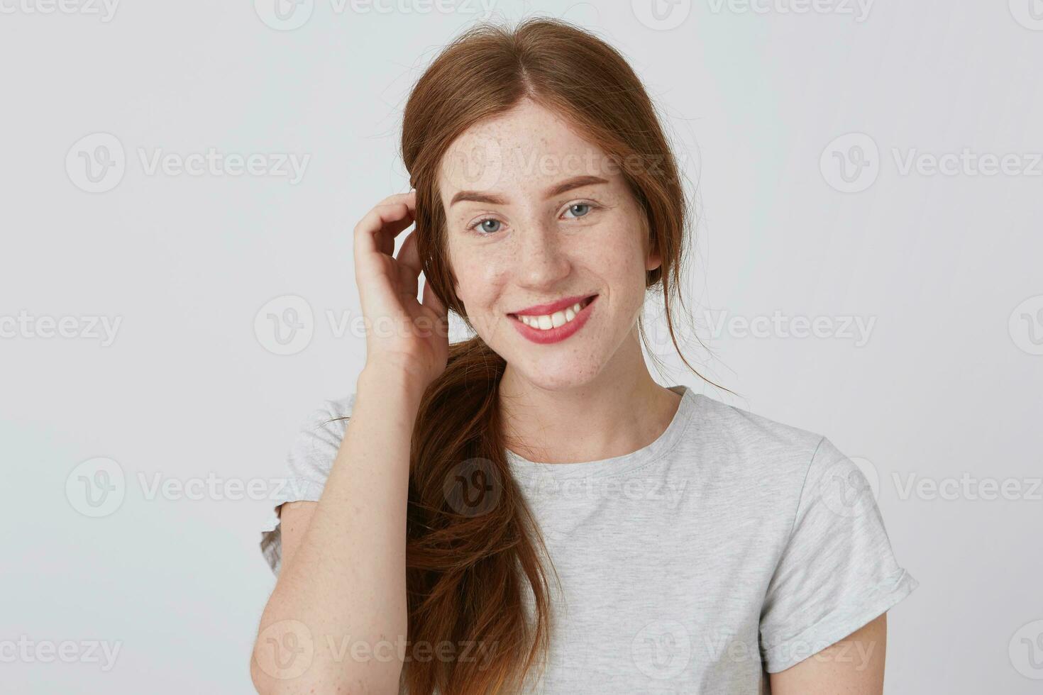 ritratto di sorridente carino testa Rossa giovane donna con lungo capelli e lentiggini sembra soddisfatto e si sente contento isolato al di sopra di bianca sfondo sembra direttamente nel telecamera foto