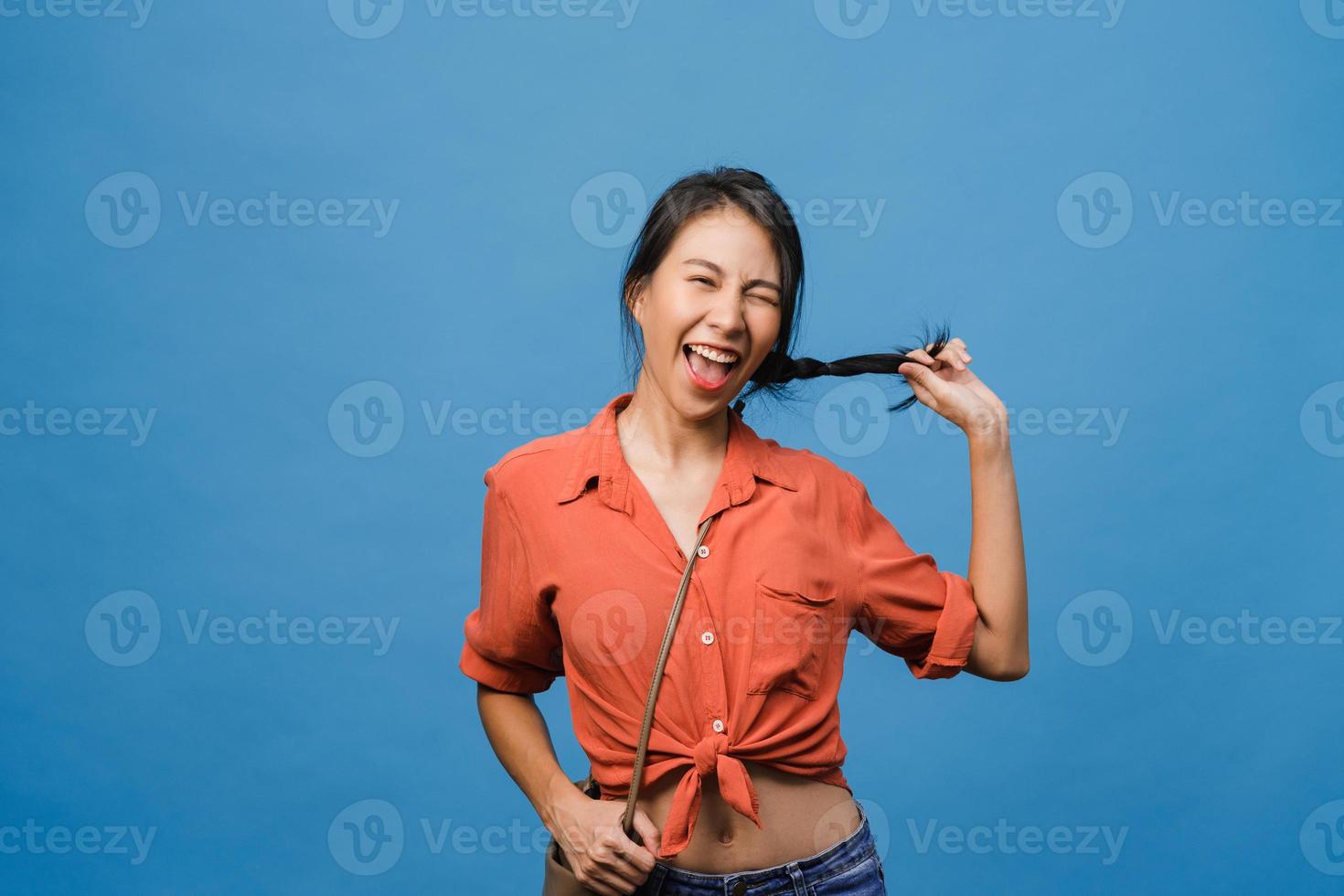 giovane donna asiatica con espressione positiva, sorriso ampiamente, vestita con abiti casual e guardando la telecamera su sfondo blu. felice adorabile donna felice esulta successo. concetto di espressione facciale. foto