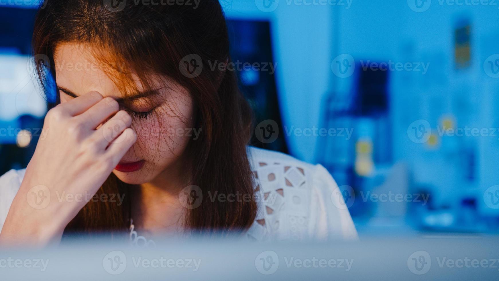 donne asiatiche freelance che utilizzano il duro lavoro del laptop nel nuovo ufficio domestico normale. lavoro da sovraccarico domestico di notte, lavoro a distanza, autoisolamento, distanza sociale, quarantena per la prevenzione del virus corona. foto