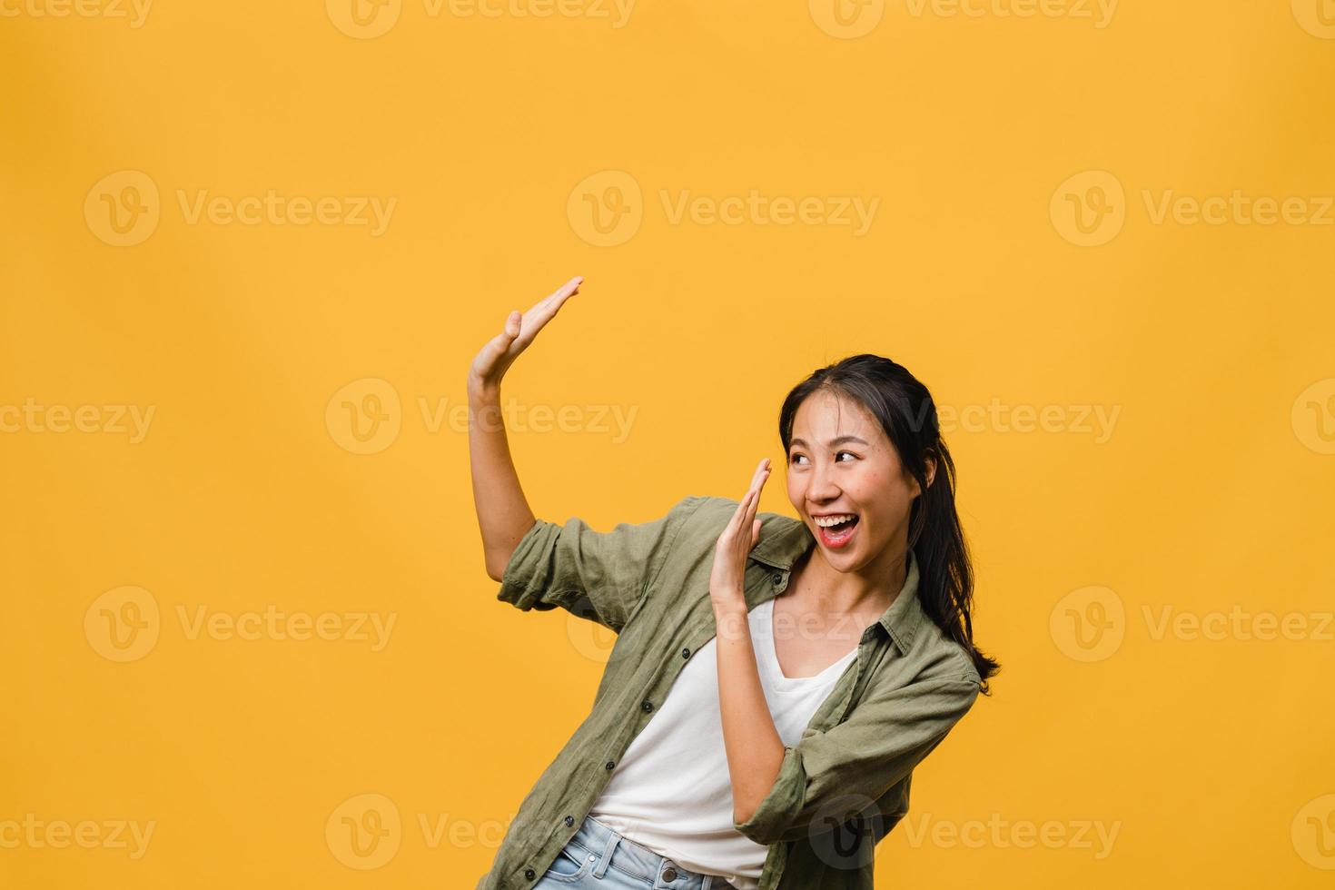 ritratto di giovane donna asiatica con espressione positiva, sorriso ampiamente, vestita con abiti casual su sfondo giallo. felice adorabile donna felice esulta successo. concetto di espressione facciale. foto
