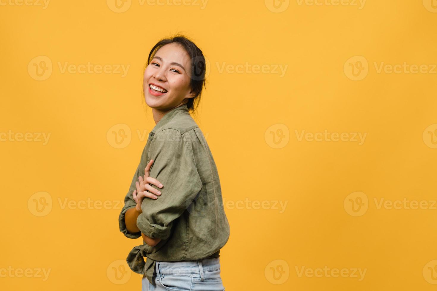 ritratto di giovane donna asiatica con espressione positiva, braccia incrociate, sorriso ampiamente, vestita con abiti casual e guardando la telecamera su sfondo giallo. felice adorabile donna felice esulta successo. foto