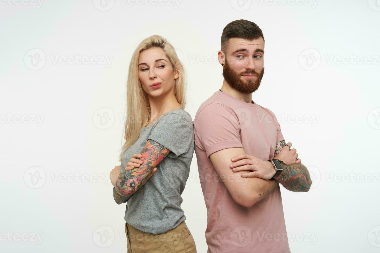 interno tiro di giovane tatuato attraente coppia conservazione loro mani piegato mentre guardare astutamente su ogni Altro, essere isolato al di sopra di bianca sfondo foto