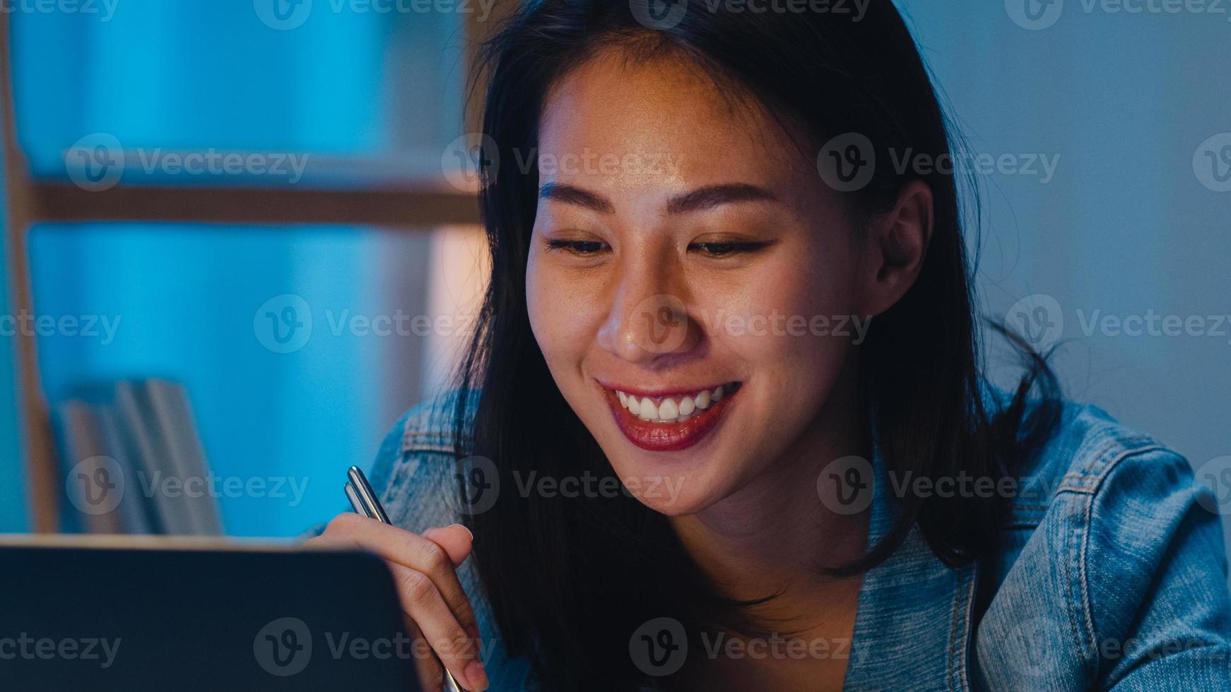 asia donne d'affari intelligenti freelance che mangiano noodles istantanei mentre lavorano al laptop nel soggiorno di casa di notte. la giovane ragazza asiatica felice che si siede sulla scrivania fa gli straordinari, godetevi il tempo di relax. foto