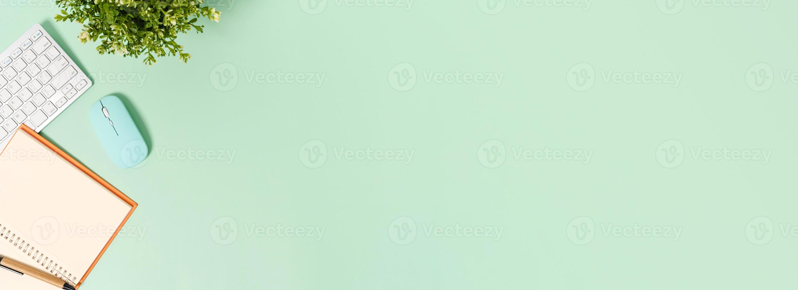 foto piatta creativa della scrivania dell'area di lavoro. scrivania da ufficio vista dall'alto con tastiera, mouse e taccuino nero mockup aperto su sfondo di colore verde pastello. vista dall'alto mock up con la fotografia dello spazio di copia.
