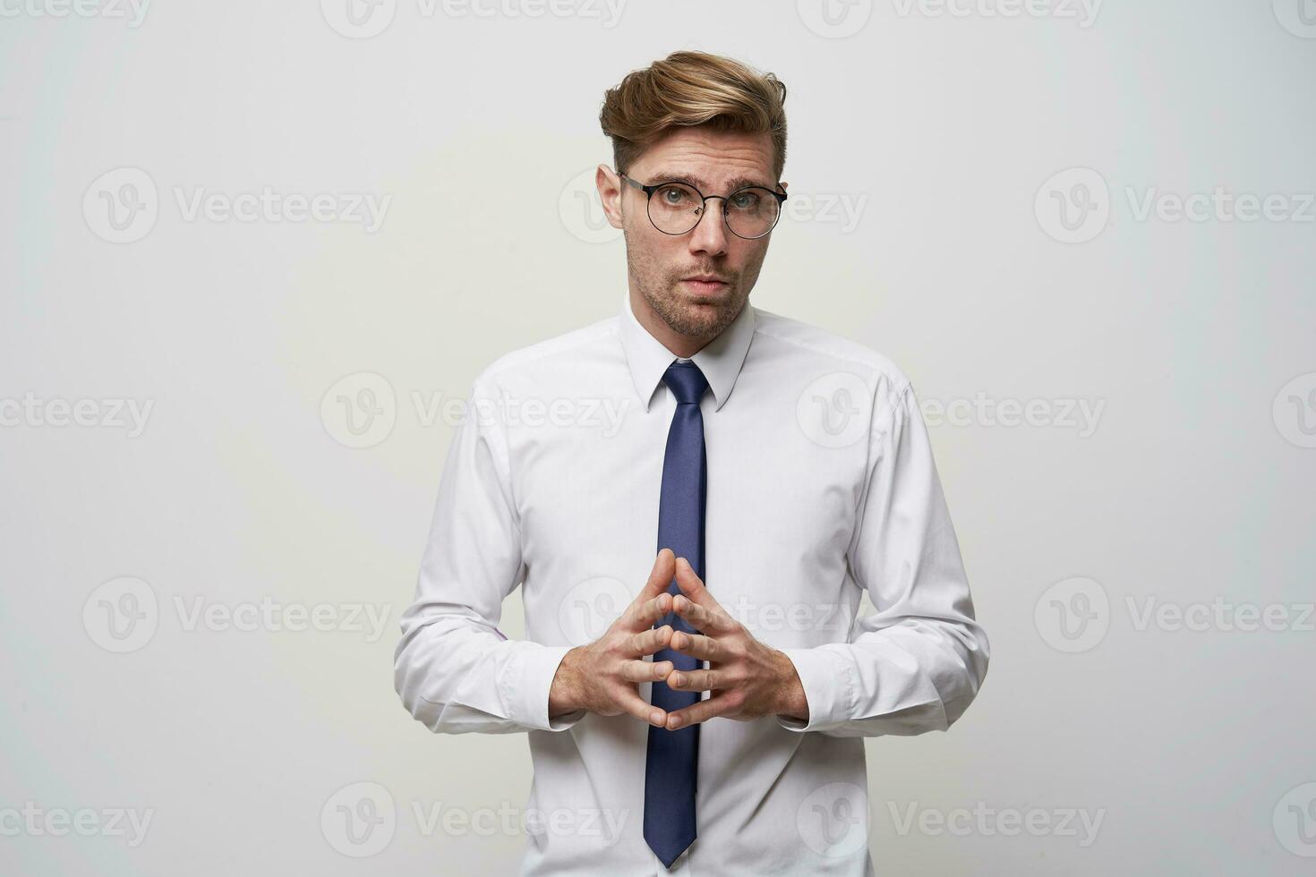 un' giovane uomo sta con il suo dita piegato nel davanti, parlando per il suo capo, dando lui un' rapporto o presentazione. sembra attraverso occhiali, un' poco nerd, teso, su un' bianca sfondo foto