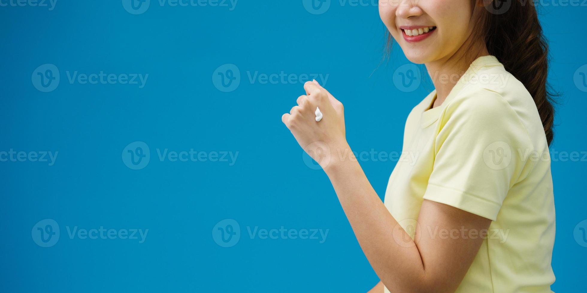 giovane ragazza asiatica che applica crema protettiva sulle mani isolate su sfondo blu. copia spazio per inserire un testo, un messaggio per la pubblicità. area pubblicitaria, mockup di contenuti promozionali. foto
