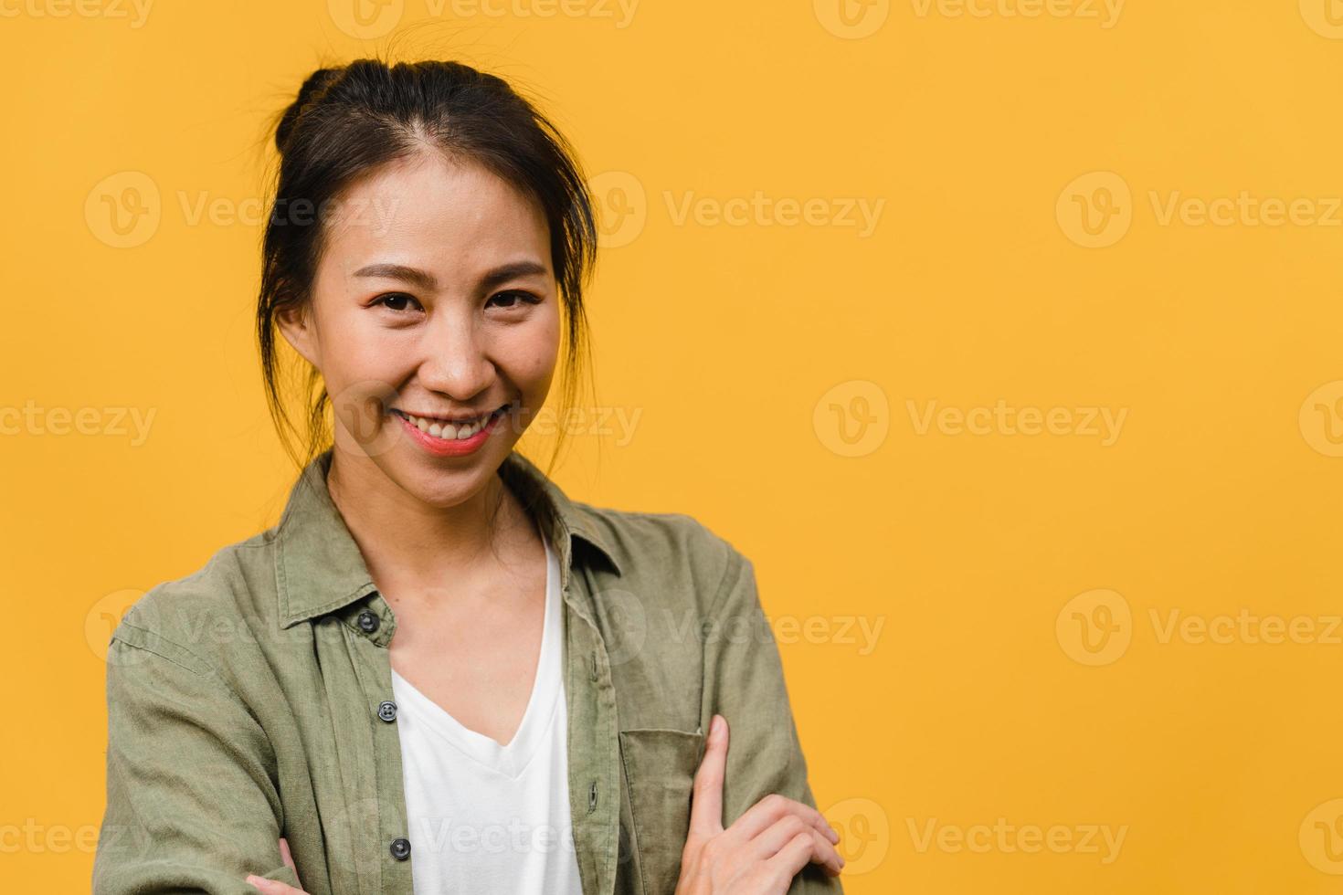 ritratto di giovane donna asiatica con espressione positiva, braccia incrociate, sorriso ampiamente, vestita con abiti casual e guardando la telecamera su sfondo giallo. felice adorabile donna felice esulta successo. foto