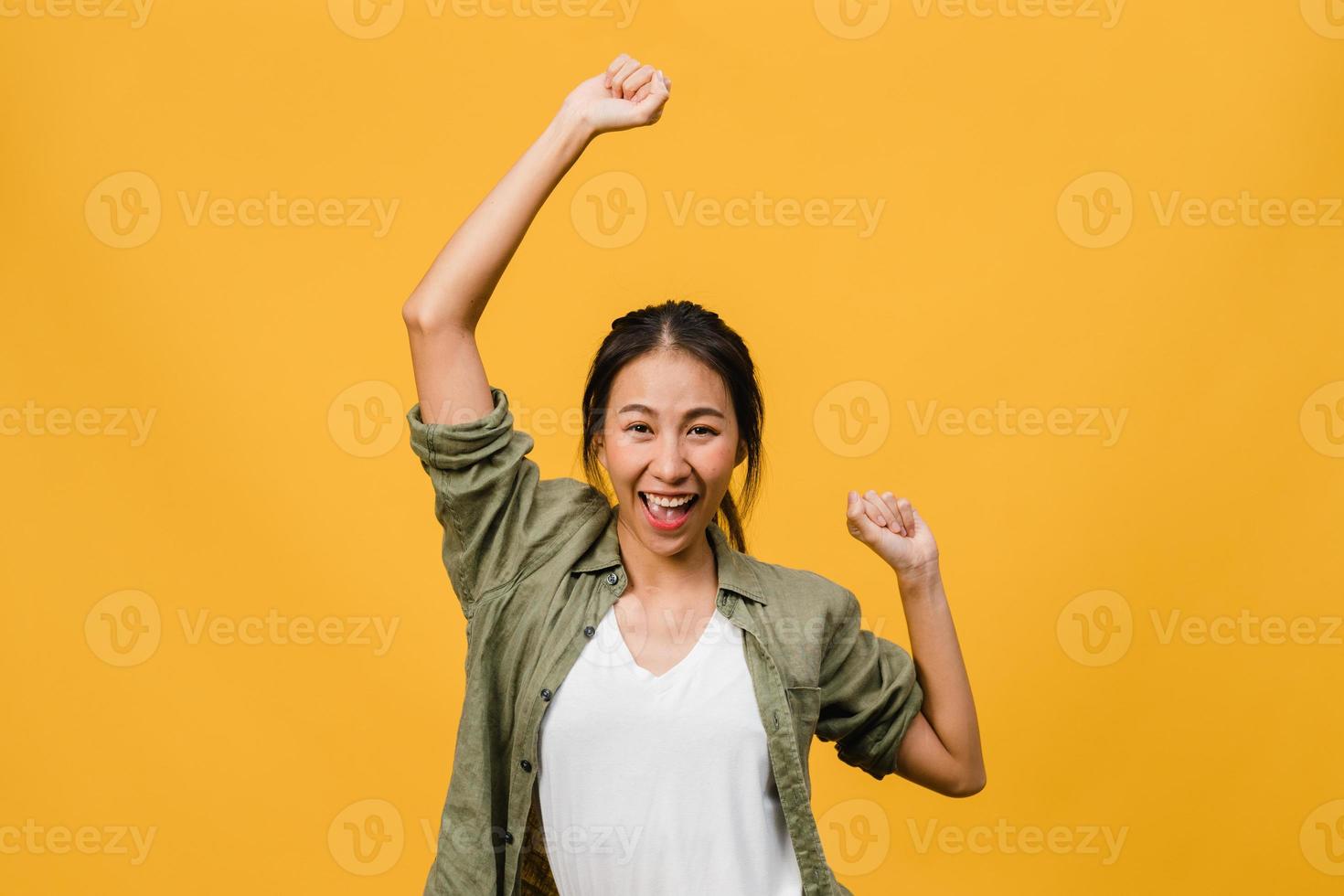 giovane donna asiatica con espressione positiva, gioiosa ed eccitante, vestita di stoffa casual su sfondo giallo con spazio vuoto. felice adorabile donna felice esulta successo. concetto di espressione facciale. foto