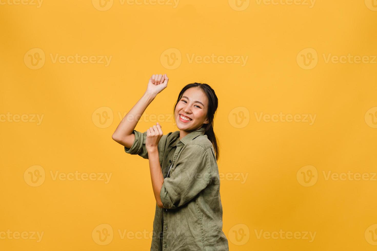 giovane donna asiatica con espressione positiva, gioiosa ed eccitante, vestita di stoffa casual su sfondo giallo con spazio vuoto. felice adorabile donna felice esulta successo. concetto di espressione facciale. foto