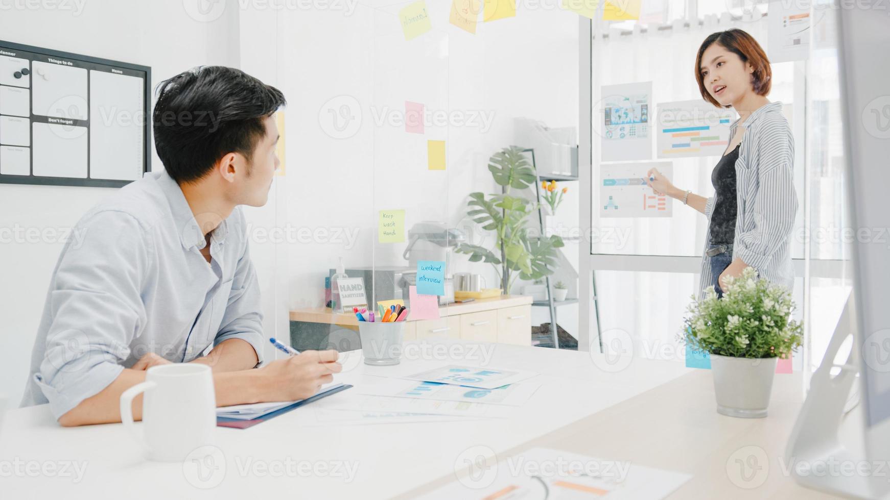 uomini d'affari asiatici che incontrano brainstorming conducendo idee di presentazione aziendale progettano colleghi e indossano una maschera protettiva per il viso nel nuovo ufficio normale. stile di vita e lavoro dopo il virus corona. foto