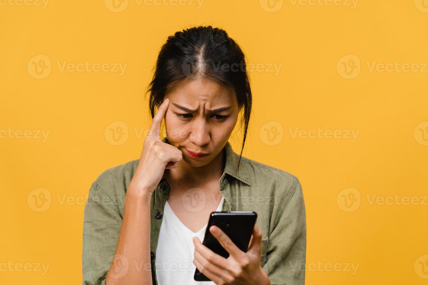 pensando di sognare la giovane donna asiatica che usa il telefono con espressione positiva, vestita con un panno casual sentendo felicità e stando isolata su sfondo giallo. felice adorabile donna felice esulta successo. foto