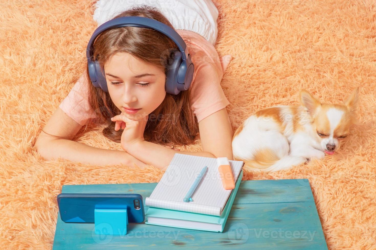 ragazza che studia online. una studentessa sta guardando una lezione su uno smartphone e c'è un cane nelle vicinanze. foto