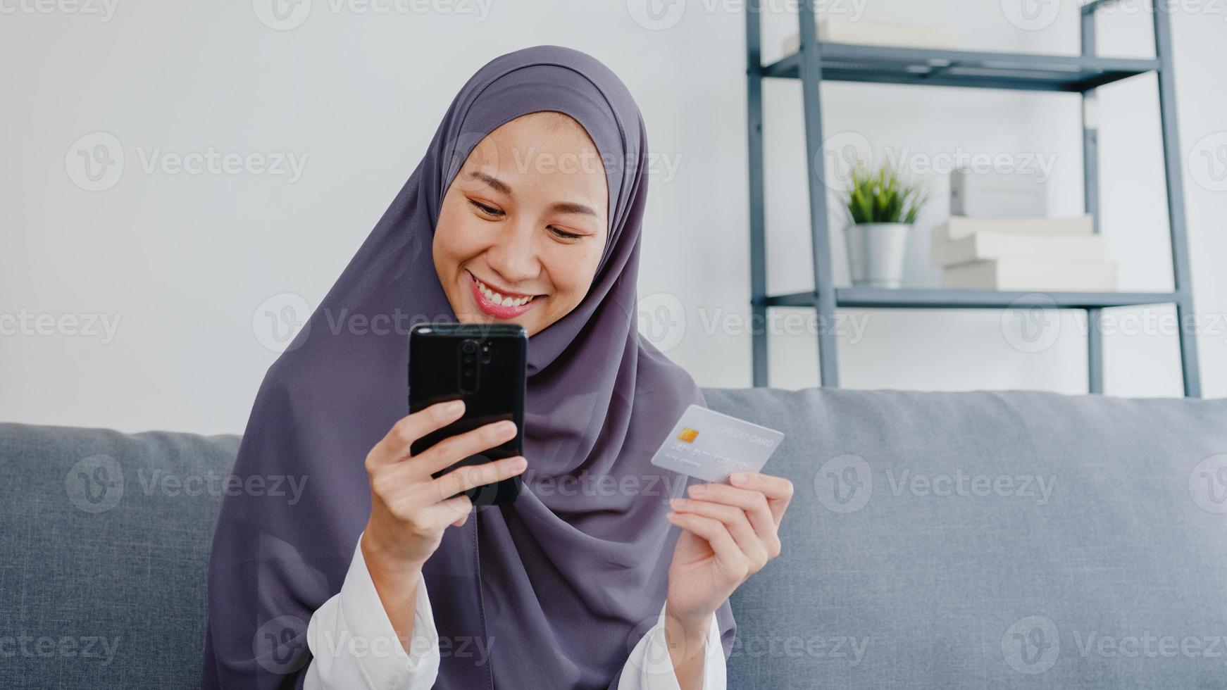 asia la signora musulmana usa lo smartphone, acquista la carta di credito e acquista internet e-commerce nel soggiorno di casa. resta a casa, shopping online, autoisolamento, distanza sociale, quarantena per coronavirus. foto