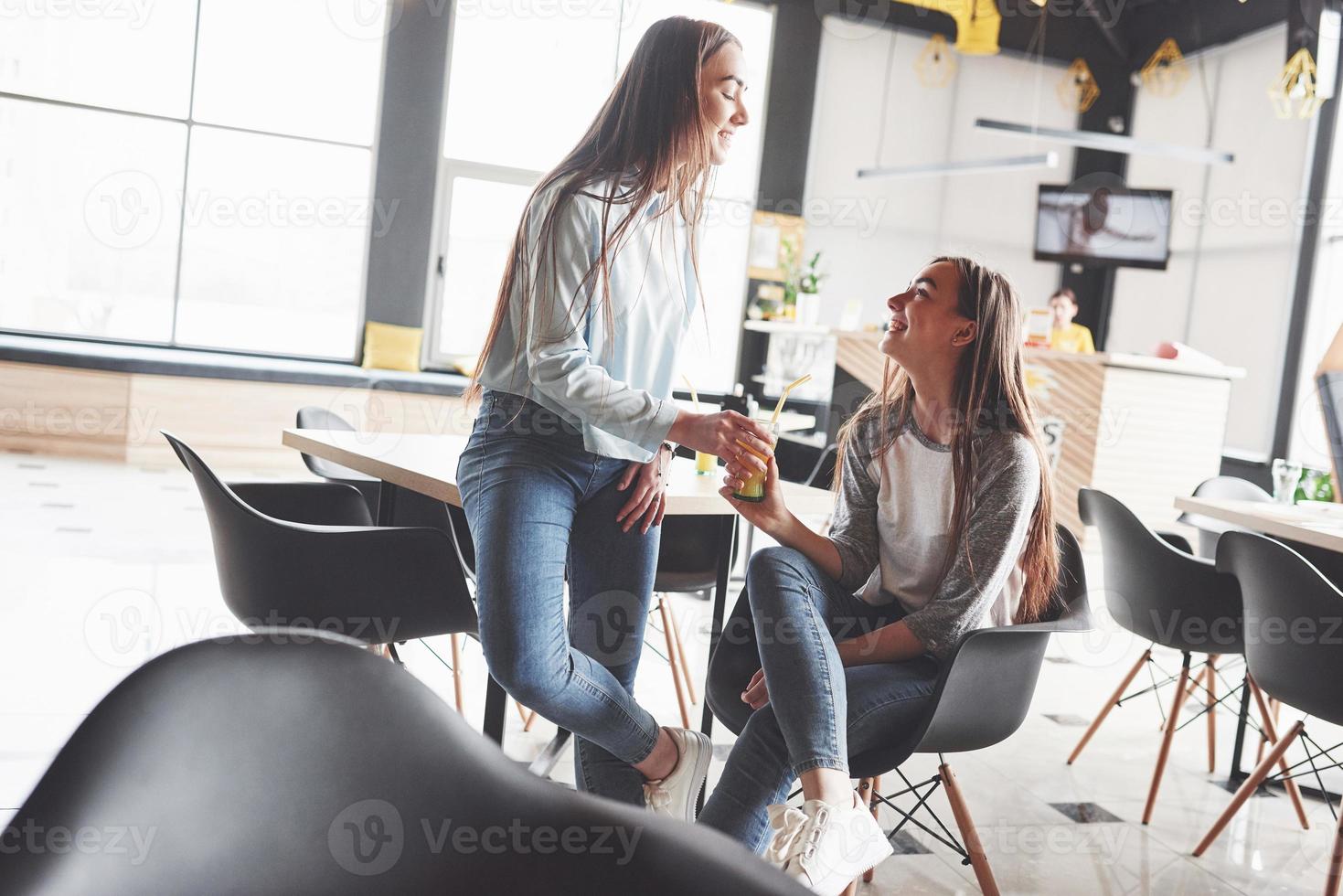 due bellissime gemelle trascorrono del tempo a bere succo di frutta. sorelle che si rilassano in un bar e si divertono insieme foto