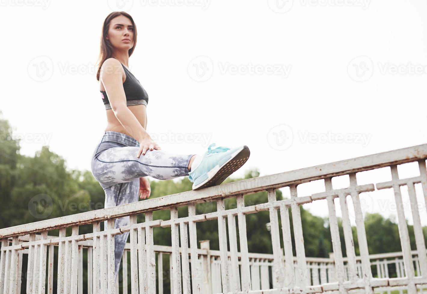 una bella bruna atleta esegue esercizi all'aperto foto