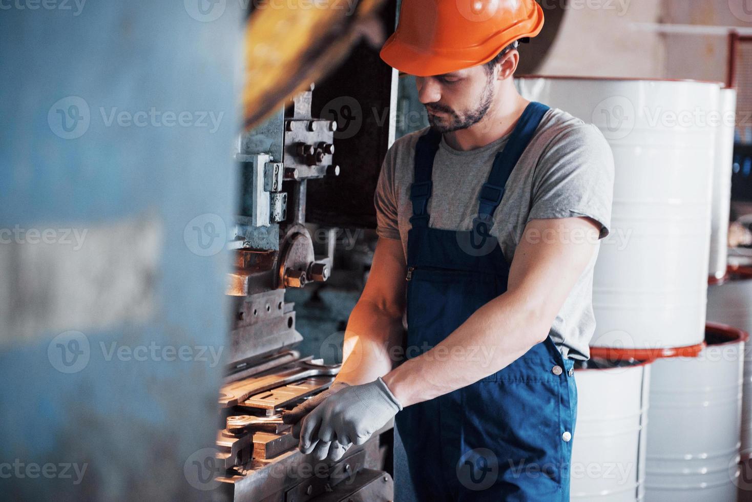 ritratto di un giovane lavoratore con un elmetto in una grande fabbrica di riciclaggio dei rifiuti. l'ingegnere controlla il lavoro di macchine e altre attrezzature foto