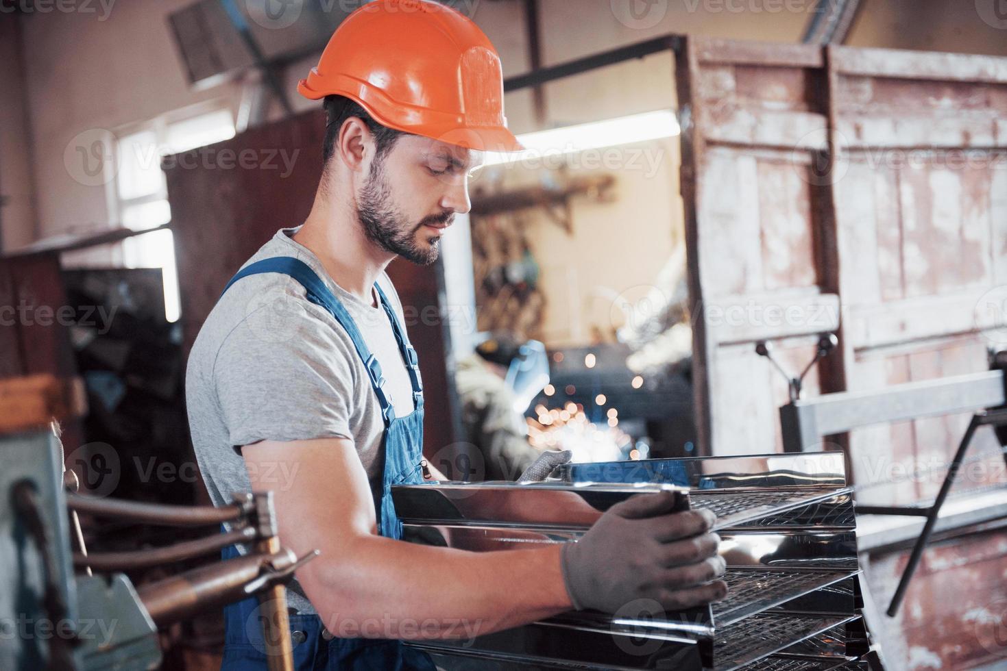 ritratto di un giovane lavoratore con un elmetto in una grande fabbrica di riciclaggio dei rifiuti. l'ingegnere controlla il lavoro di macchine e altre attrezzature foto