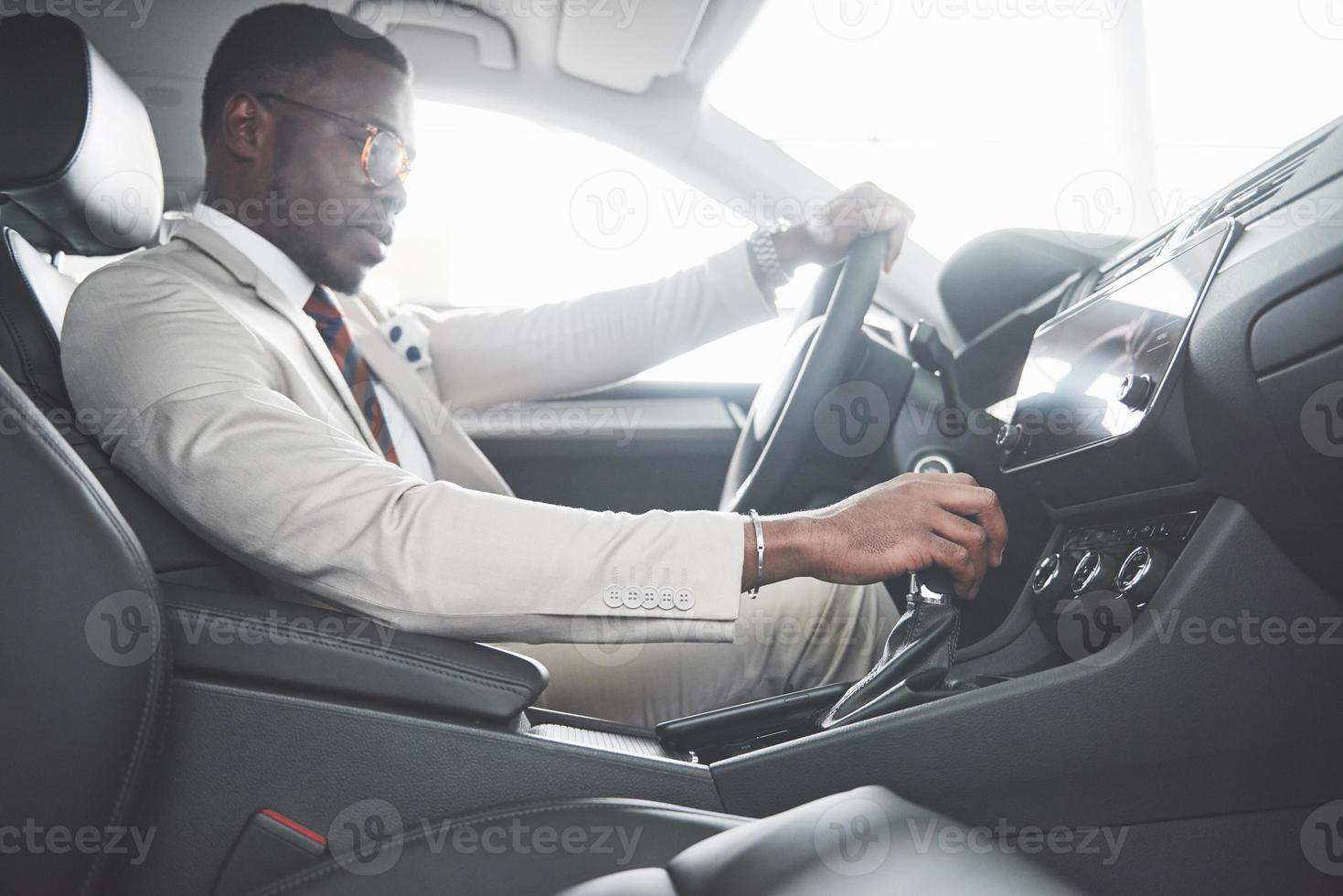 elegante uomo d'affari nero seduto al volante della nuova auto di lusso. ricco uomo afroamericano foto