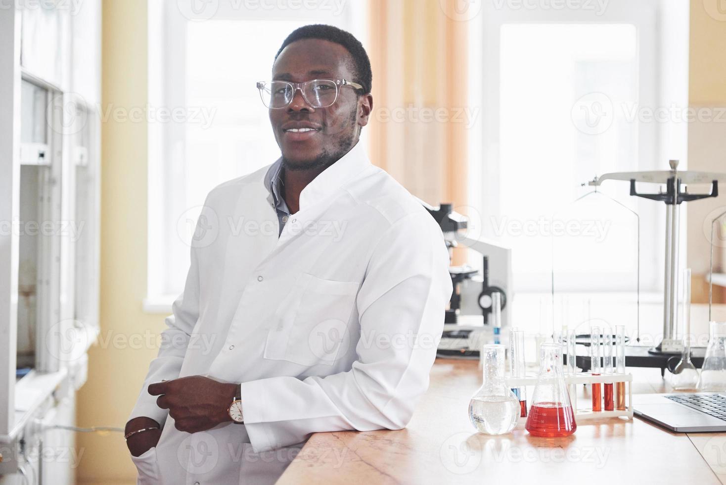 un lavoratore afroamericano lavora in un laboratorio conducendo esperimenti. foto