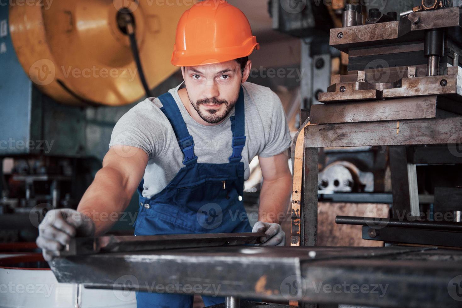 ritratto di un giovane lavoratore con un elmetto in una grande fabbrica di riciclaggio dei rifiuti. l'ingegnere controlla il lavoro di macchine e altre attrezzature foto