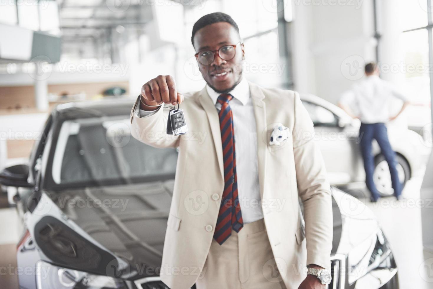 il giovane attraente uomo d'affari nero compra una nuova auto, i sogni diventano realtà foto