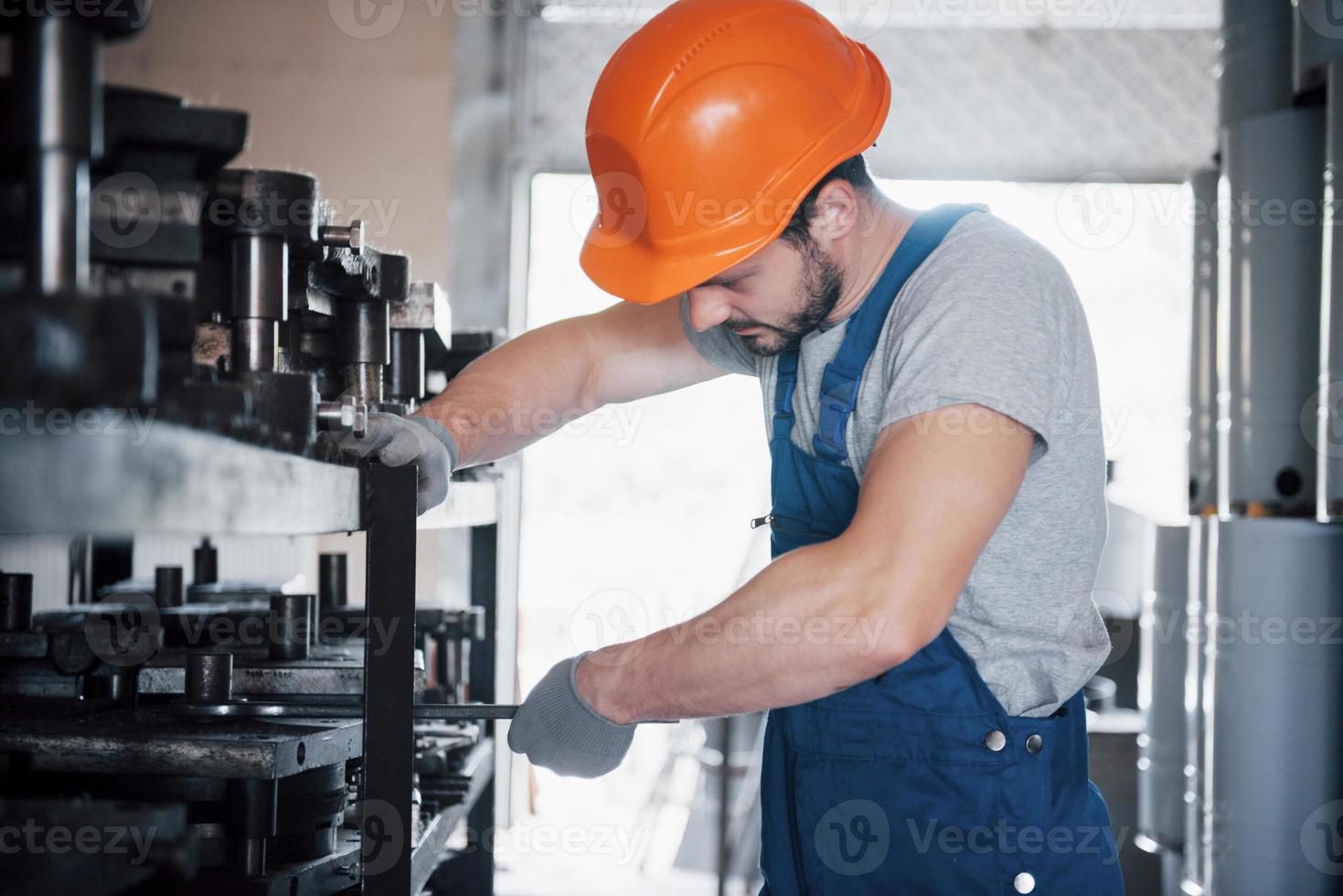 ritratto di un giovane lavoratore con un elmetto in una grande fabbrica di riciclaggio dei rifiuti. l'ingegnere controlla il lavoro di macchine e altre attrezzature foto