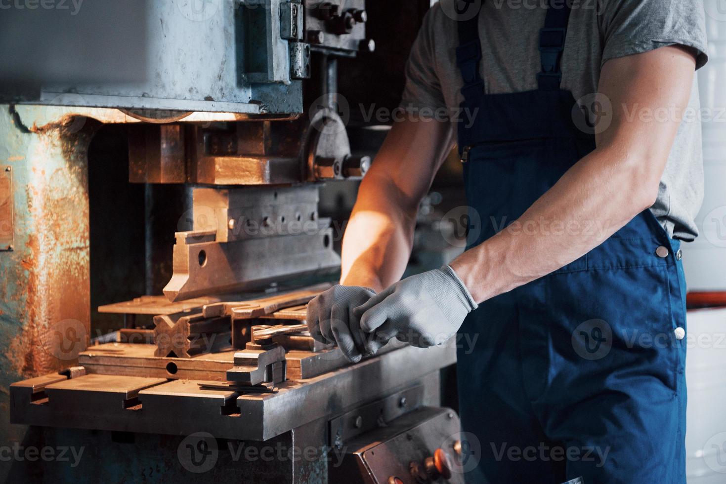 ritratto di un giovane lavoratore con un elmetto in un grande impianto di lavorazione dei metalli. l'ingegnere serve le macchine e produce parti per apparecchiature a gas foto