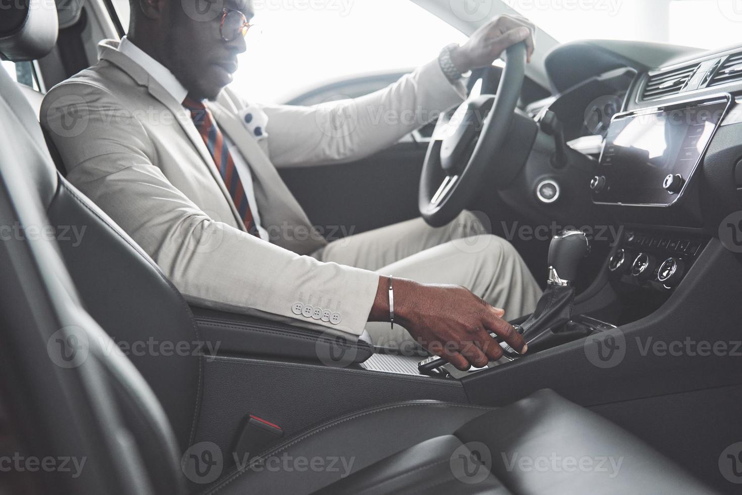 elegante uomo d'affari nero seduto al volante della nuova auto di lusso. ricco uomo afroamericano foto