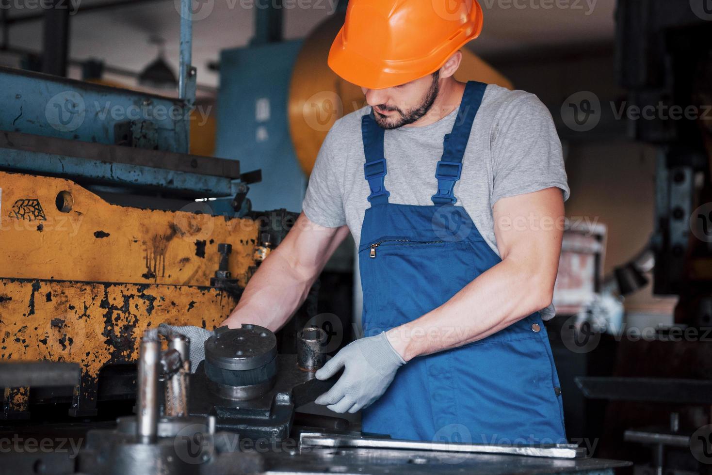 ritratto di un giovane lavoratore con un elmetto in una grande fabbrica di riciclaggio dei rifiuti. l'ingegnere controlla il lavoro di macchine e altre attrezzature foto