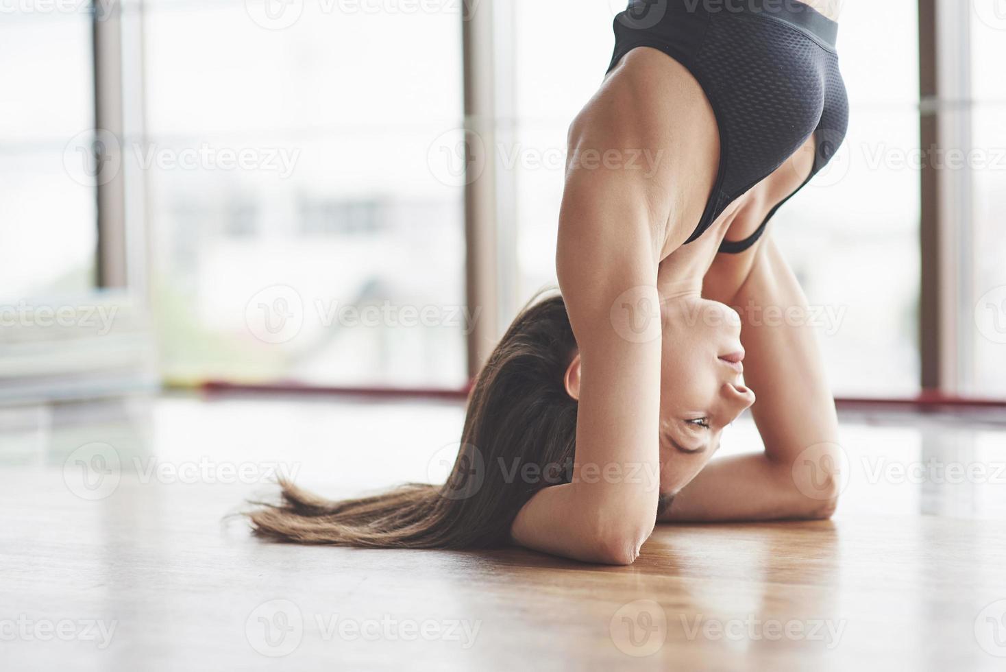 una bella donna di yoga che pratica in una spaziosa palestra leggera foto