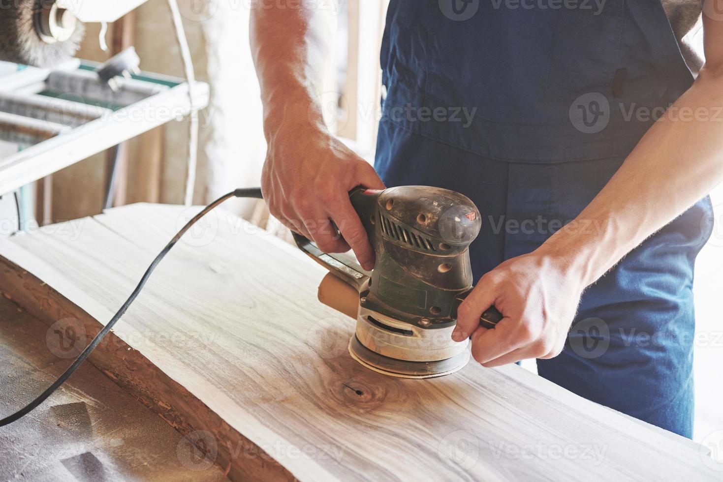 un giovane falegname e una maschera lucidano una rastrelliera di legno in studio. foto