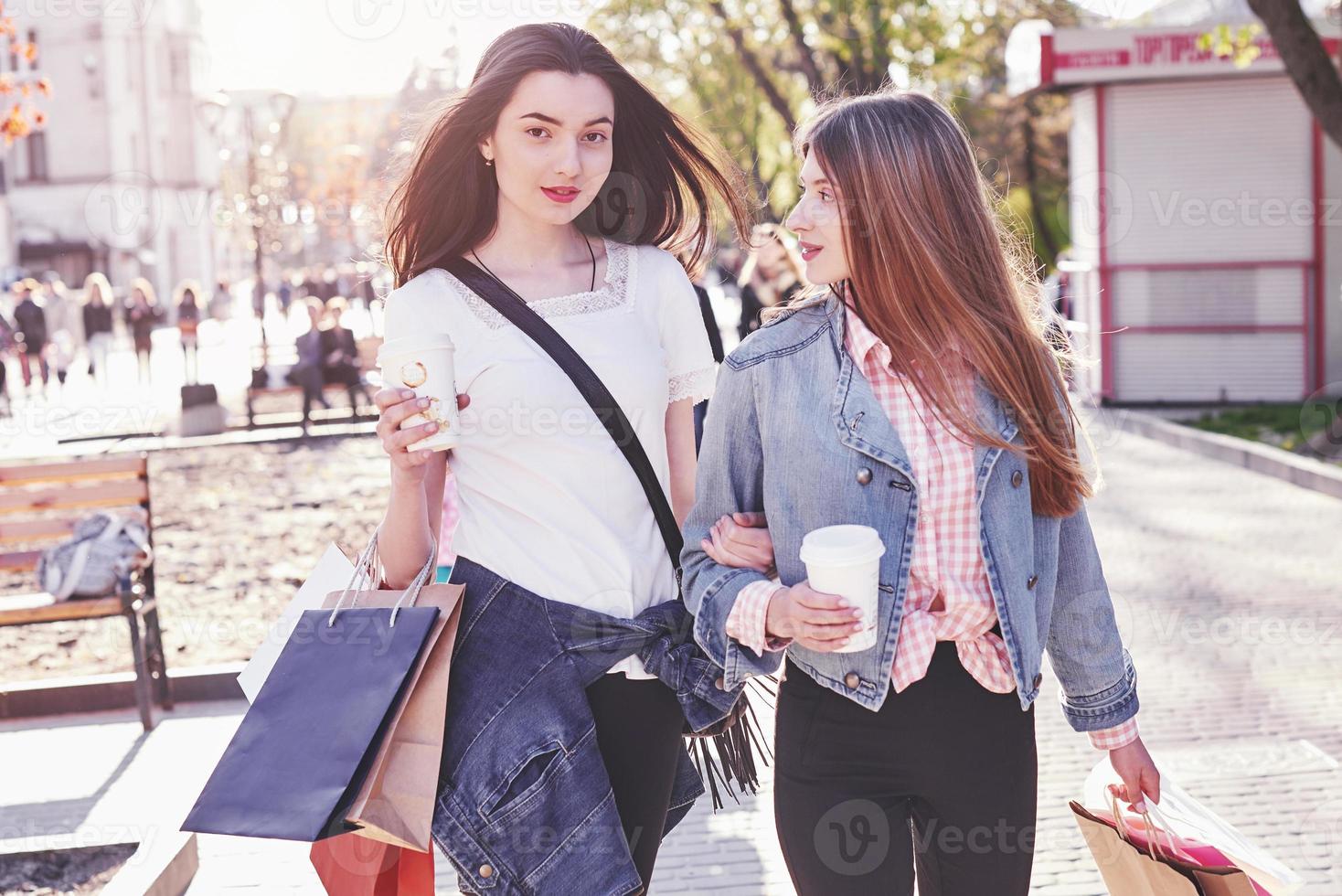 giovani ragazze attraenti con borse della spesa e caffè in città foto