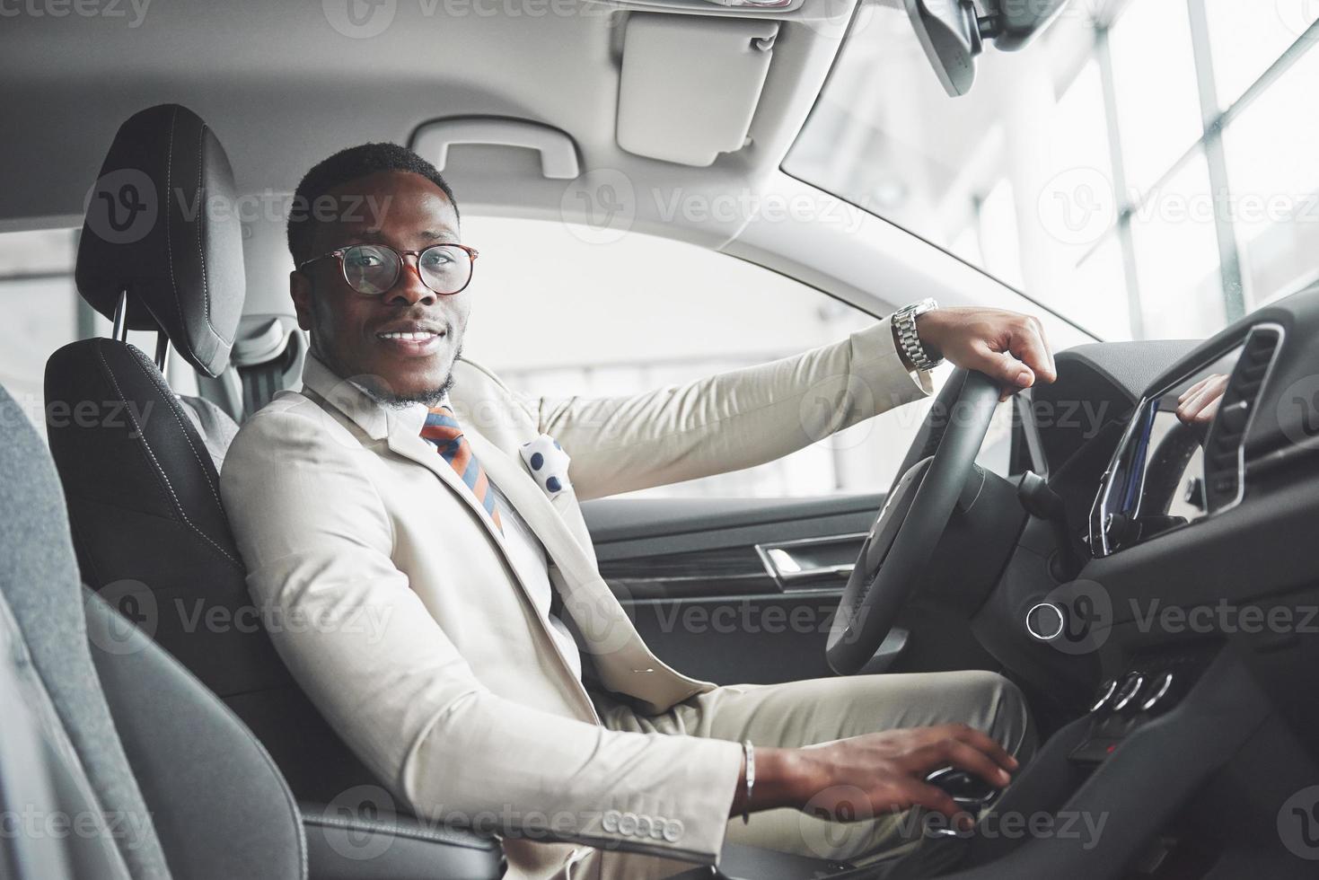 elegante uomo d'affari nero seduto al volante della nuova auto di lusso. ricco uomo afroamericano foto