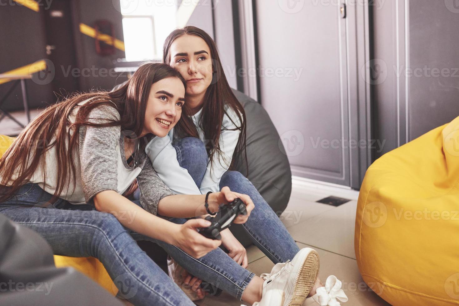 sorelle gemelle giocano sulla console. le ragazze tengono i joystick in mano e si divertono foto