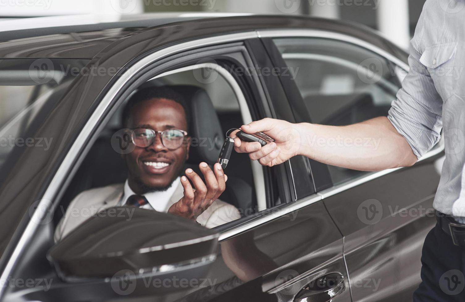 un afroamericano prende le chiavi di un'auto in una concessionaria. foto
