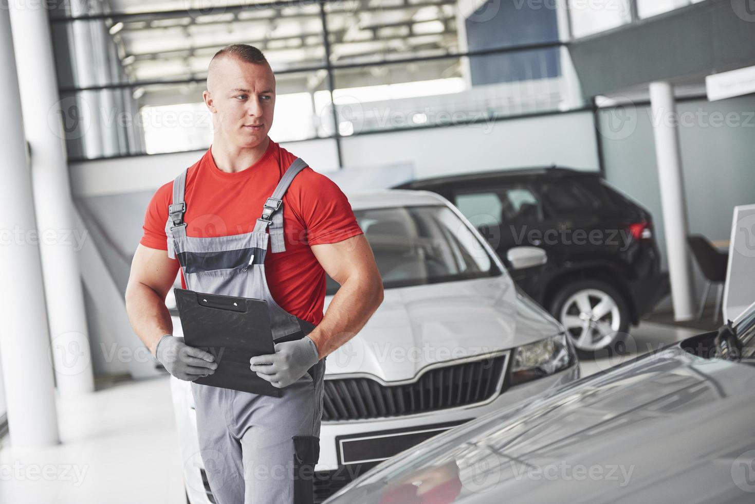 un bel giovane parla in una concessionaria di auto, riparando un'auto in un'officina. foto