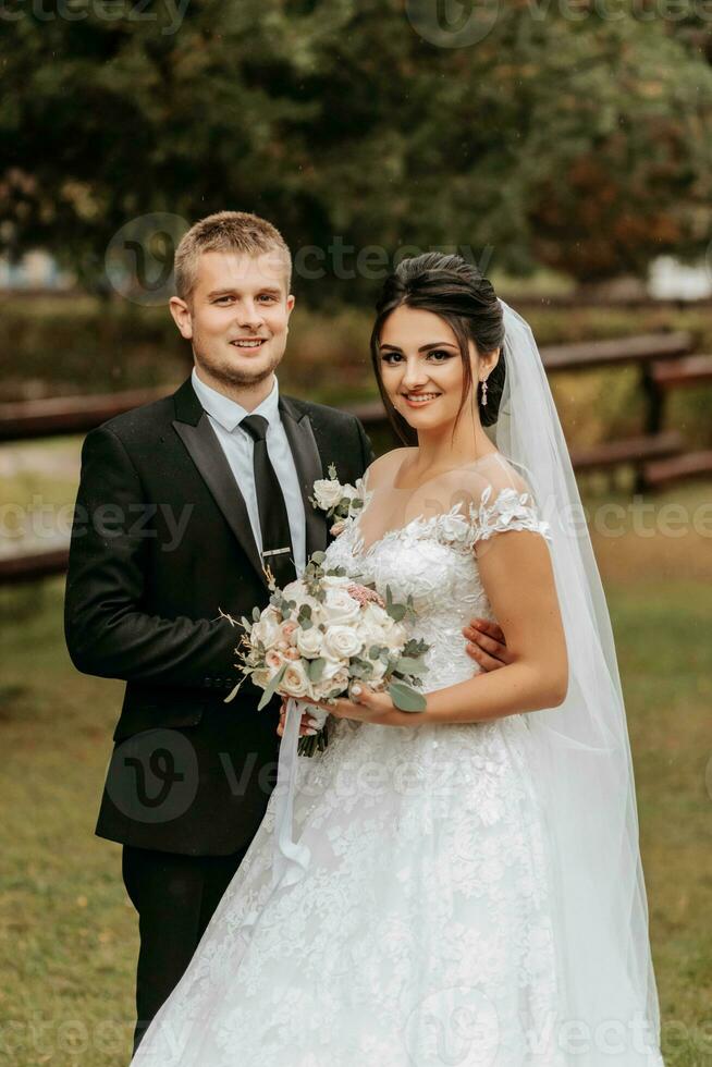 ritratto di il sposa e sposo nel il parco, il sposa e sposo Guarda in il telecamera lente. nozze camminare nel il parco foto