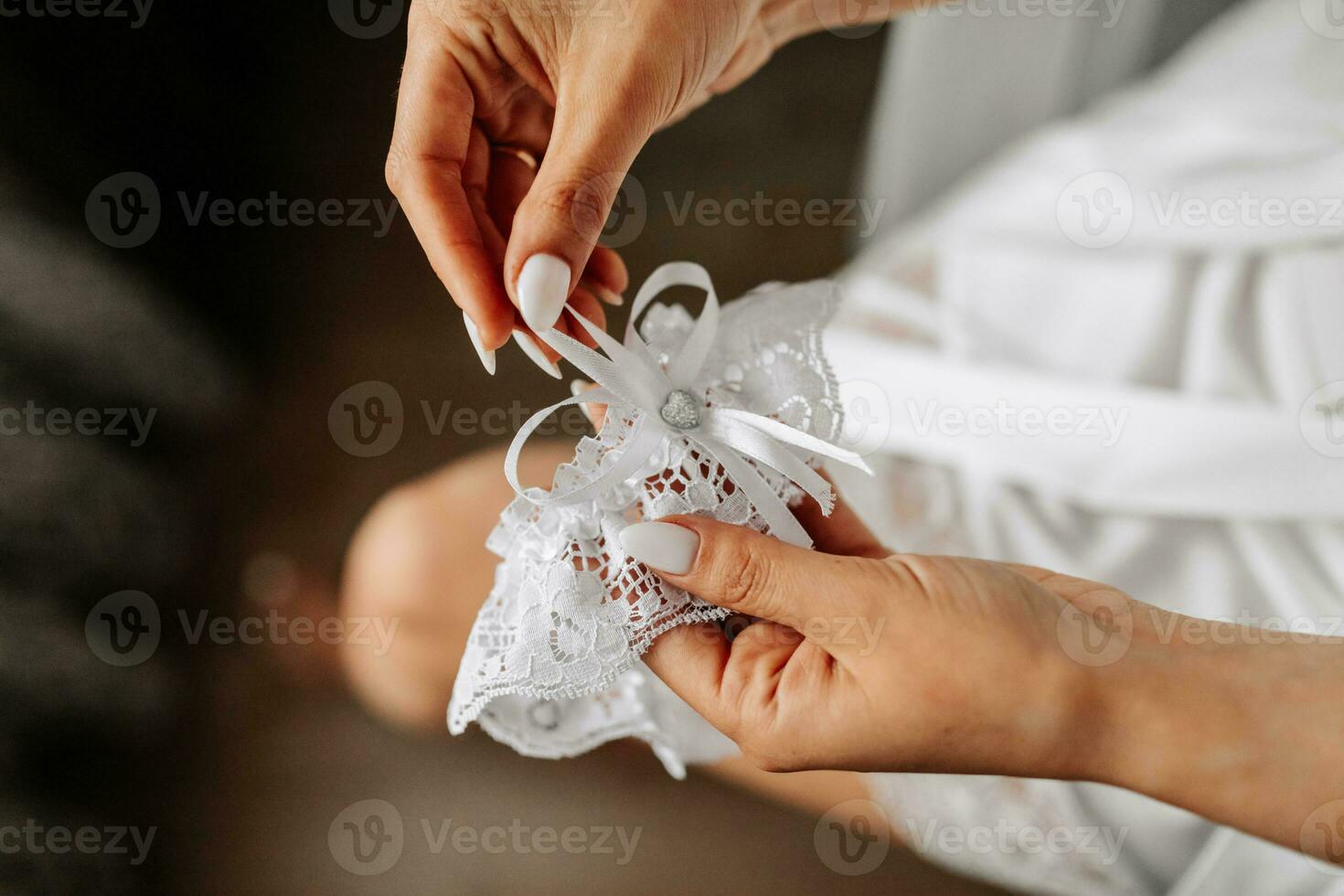 giarrettiera su il gamba di il sposa nel sua mani, avvicinamento. mattina di il sposa foto