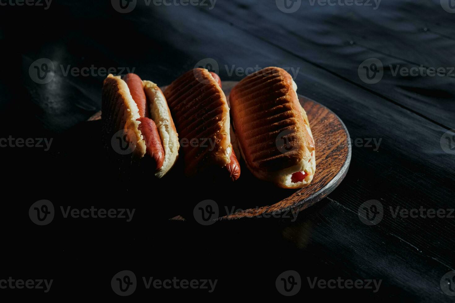 tre delizioso, appena preparato caldo cani visualizzato su un' nero di legno In piedi. concetto per un' picnic o barbecue con famiglia e gli amici. alto qualità foto