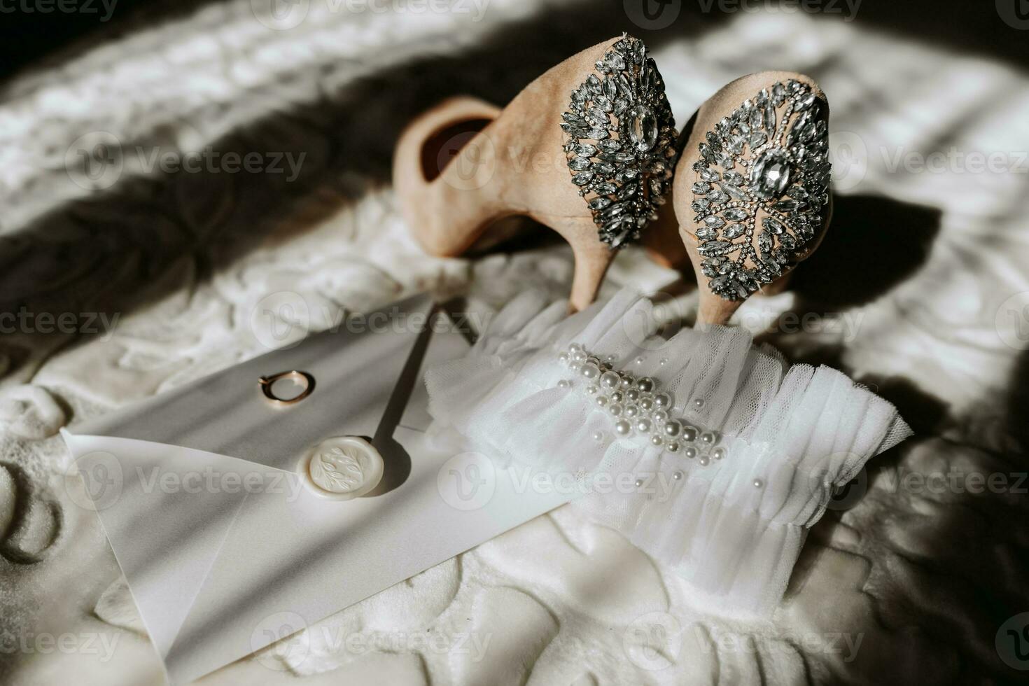 nozze scarpe di il sposa su un' alto tacco di beige colore con pietre sopra il tacco, un Busta con un' nozze voto e un' nozze squillare di il sposa è in piedi Il prossimo per esso foto