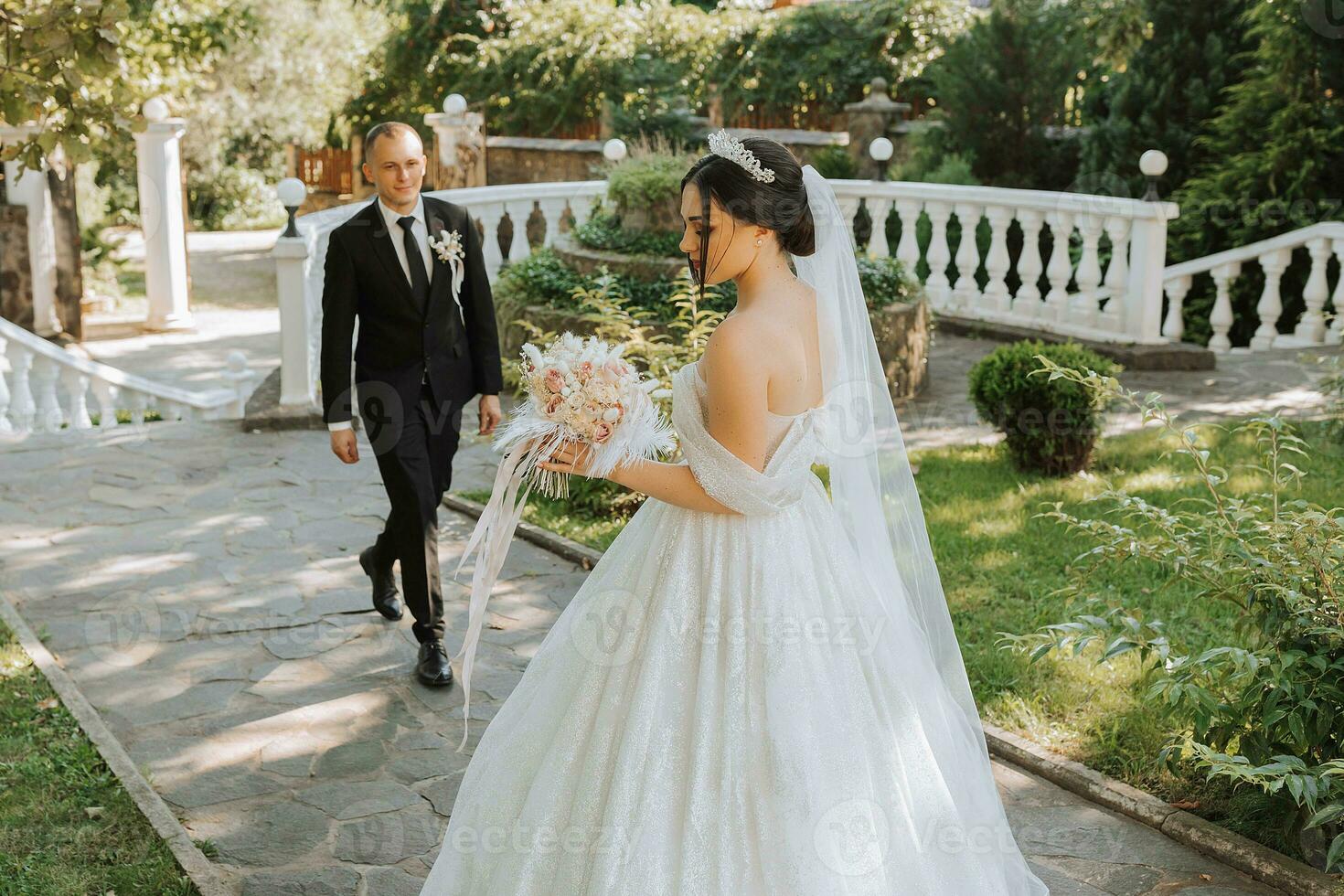 il sposa e sposo hold mani, camminare nel il giardino guardare a ogni altro foto