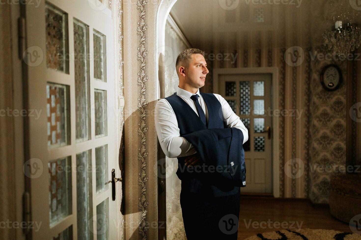 un elegante sposo è Tenere un' giacca su il suo braccio nel il suo camera. dettagli di il nozze mattina. dettagli bellezza e moda. foto
