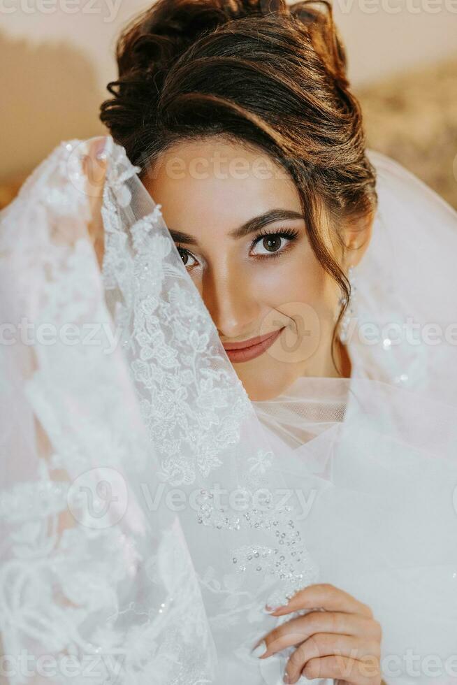 il sposa è seduta su il divano nel un' seta condimento abito. il sposa è preparazione per sua nozze foto