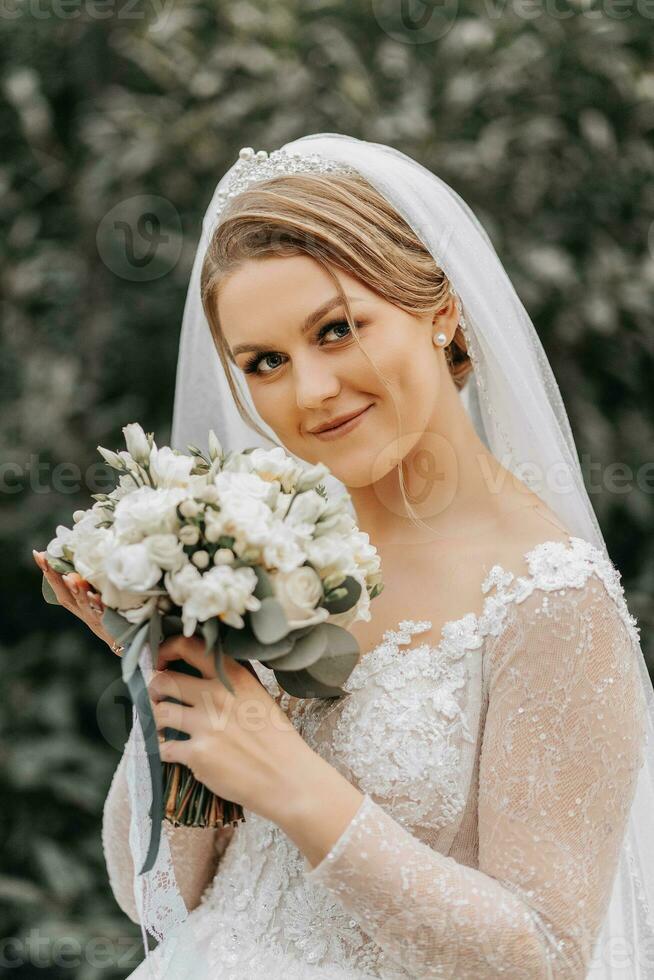 ritratto di un' bellissimo sposa con un' velo nel un' voluminoso nozze vestito e professionale trucco. avvicinamento ritratto di un' giovane bellissima sposa. nozze. foto