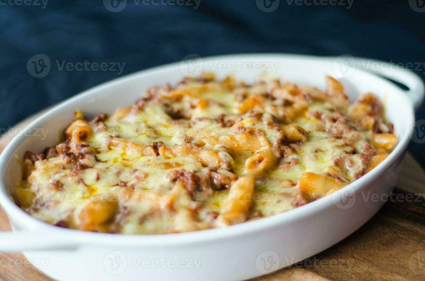 al forno pasta con formaggio nel un' bianca piatto su un' nero sfondo foto