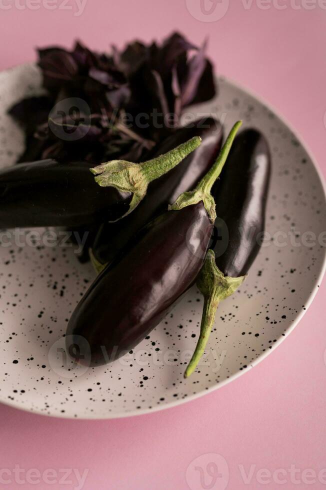 viola melanzane nel un' piatto su un' rosa sfondo. foto